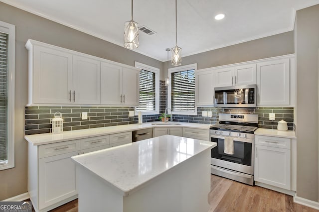 kitchen featuring white cabinets, decorative light fixtures, stainless steel appliances, and a kitchen island