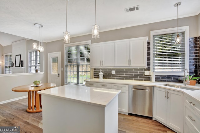 kitchen with white cabinetry, sink, hanging light fixtures, stainless steel dishwasher, and light wood-type flooring