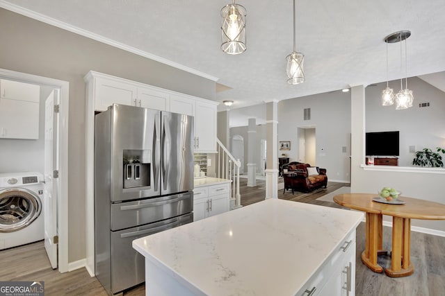 kitchen featuring white cabinets, hanging light fixtures, stainless steel refrigerator with ice dispenser, and washer / dryer