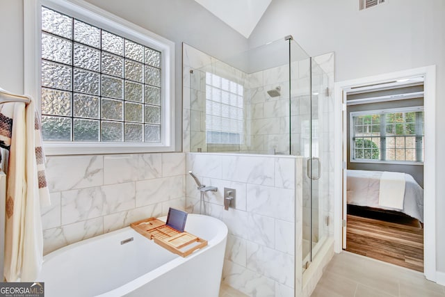 bathroom featuring a wealth of natural light, independent shower and bath, and vaulted ceiling