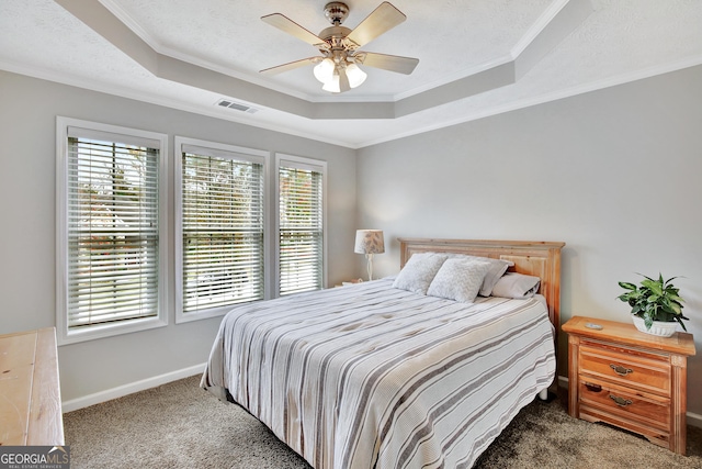 carpeted bedroom featuring a tray ceiling, ceiling fan, and crown molding