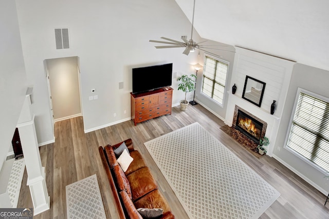 living room with light wood-type flooring, high vaulted ceiling, and ceiling fan