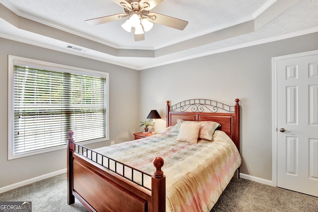 carpeted bedroom with ceiling fan, a raised ceiling, and ornamental molding