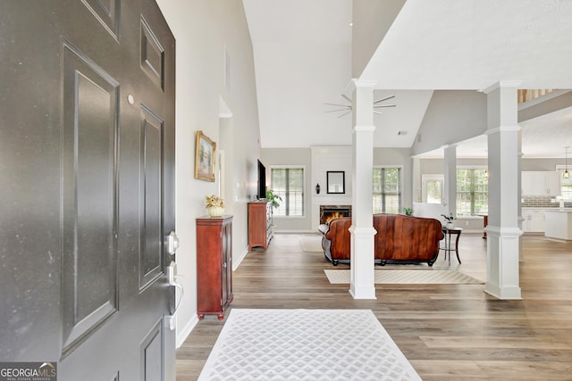 foyer featuring hardwood / wood-style floors, ceiling fan, ornate columns, and high vaulted ceiling