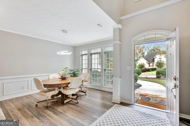 dining space with a textured ceiling, light wood-type flooring, ornamental molding, and a chandelier