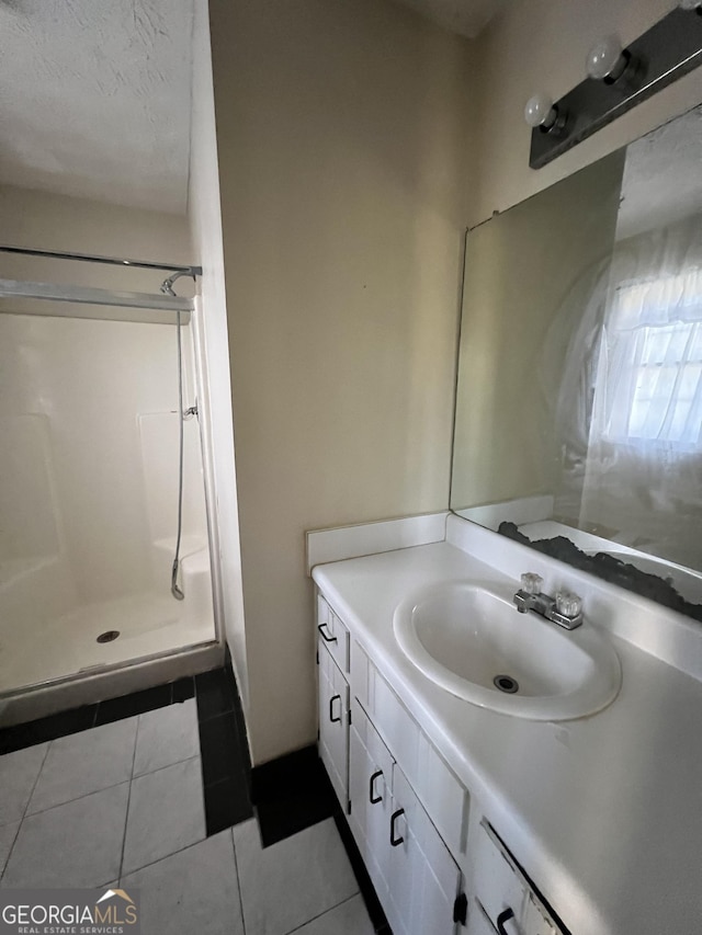 bathroom featuring tile patterned floors, a shower, vanity, and a textured ceiling