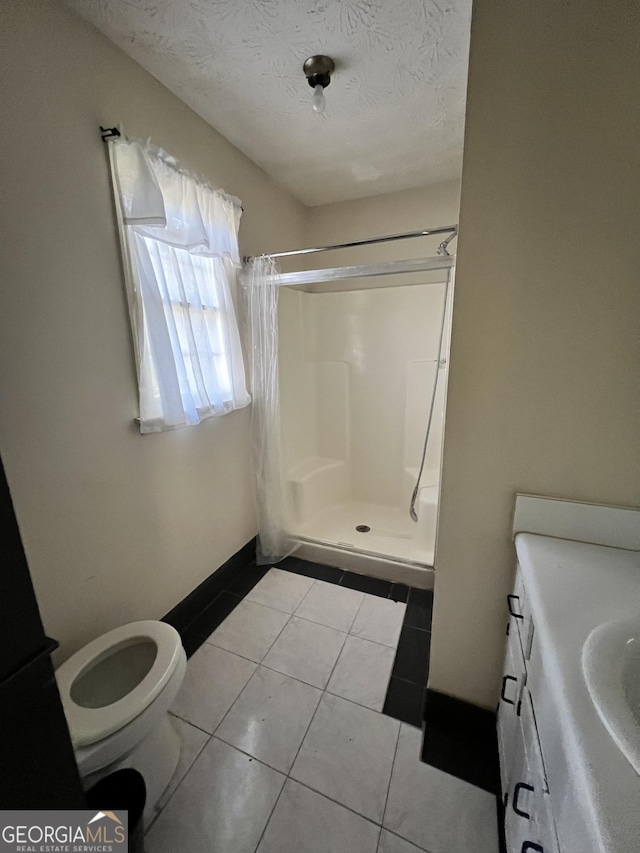 bathroom with tile patterned flooring, vanity, a textured ceiling, and walk in shower