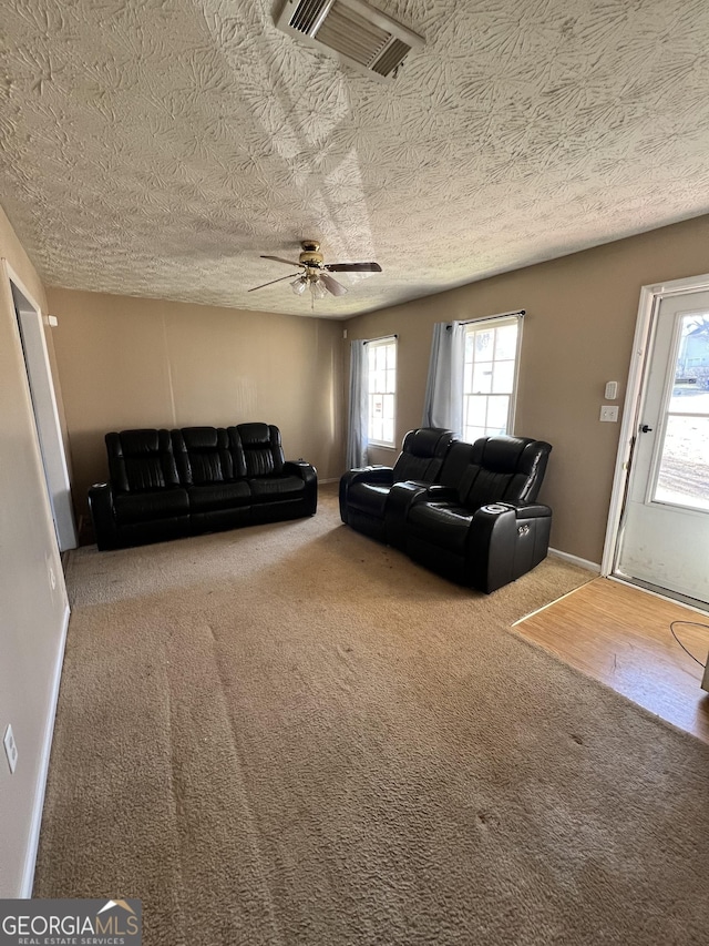 unfurnished living room featuring ceiling fan, carpet floors, and a textured ceiling