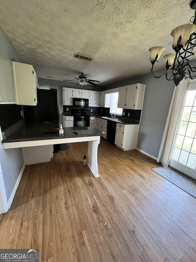 kitchen with white cabinets, a kitchen bar, kitchen peninsula, and black appliances