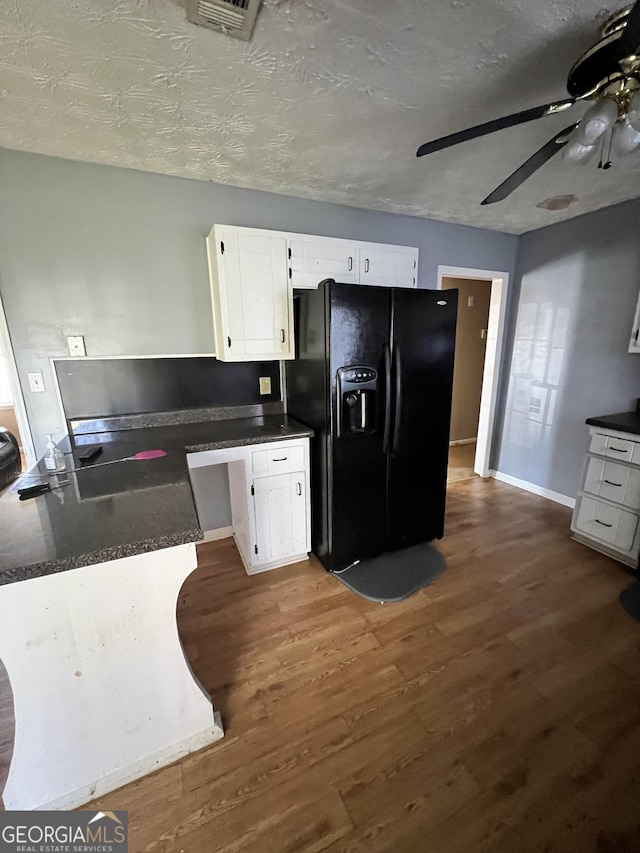 kitchen with black fridge, a textured ceiling, ceiling fan, dark wood-type flooring, and white cabinets