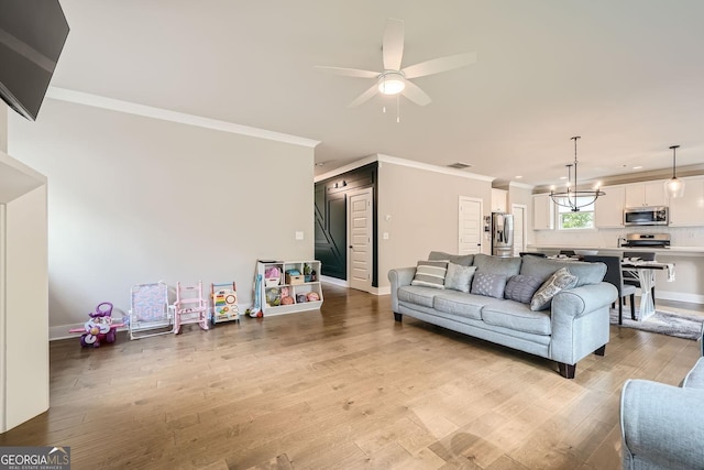 living room featuring ceiling fan with notable chandelier, light hardwood / wood-style floors, and ornamental molding