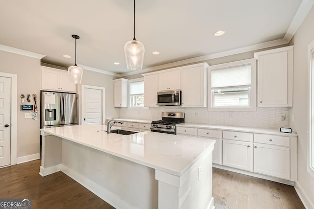 kitchen featuring pendant lighting, white cabinets, a center island with sink, sink, and stainless steel appliances