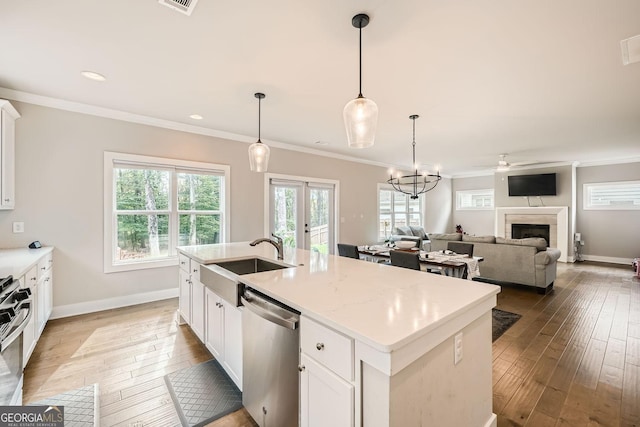 kitchen featuring white cabinetry, sink, decorative light fixtures, a center island with sink, and appliances with stainless steel finishes