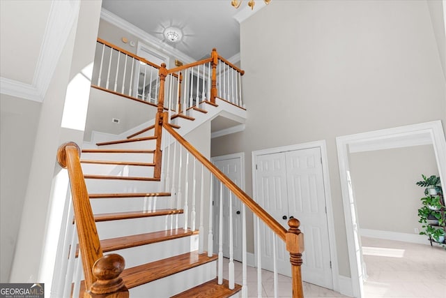 stairway with a high ceiling and crown molding