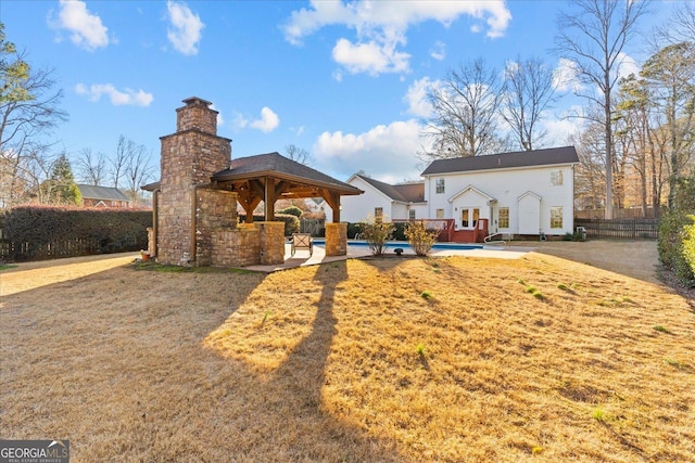 back of property featuring a gazebo, a pool, and a lawn