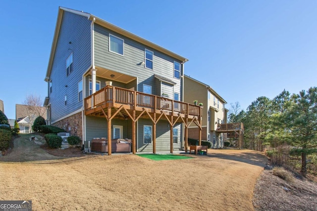 rear view of house with a patio area, a hot tub, and a deck