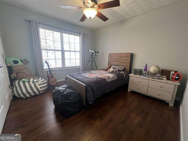 bedroom with ceiling fan, dark wood-type flooring, and a textured ceiling