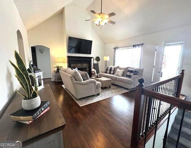 213 Moore Valley Way, Canton, GA 30115 - living room featuring arched walkways, ceiling fan, dark wood-type flooring, a fireplace, and high vaulted ceiling
