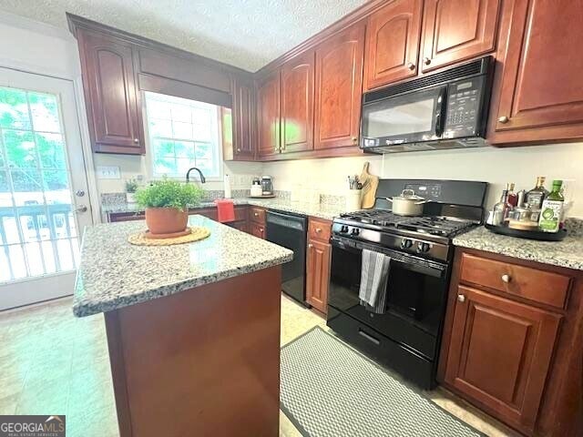 213 Moore Valley Way, Canton, GA 30115 - kitchen with black appliances, plenty of natural light, light stone counters, a center island, and a textured ceiling