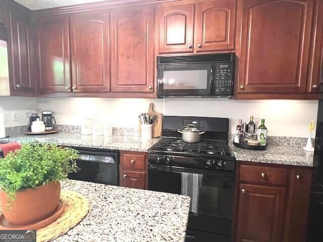 213 Moore Valley Way, Canton, GA 30115 - kitchen featuring black appliances, light stone counters, and reddish brown cabinets