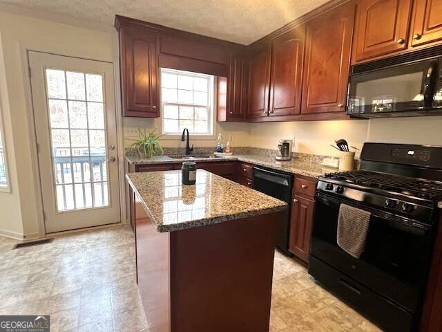 kitchen with sink, light stone counters, a textured ceiling, a kitchen island, and black appliances