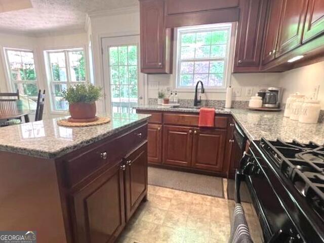 213 Moore Valley Way, Canton, GA 30115 - kitchen with light stone counters, black range with gas cooktop, ornamental molding, a center island, and a textured ceiling