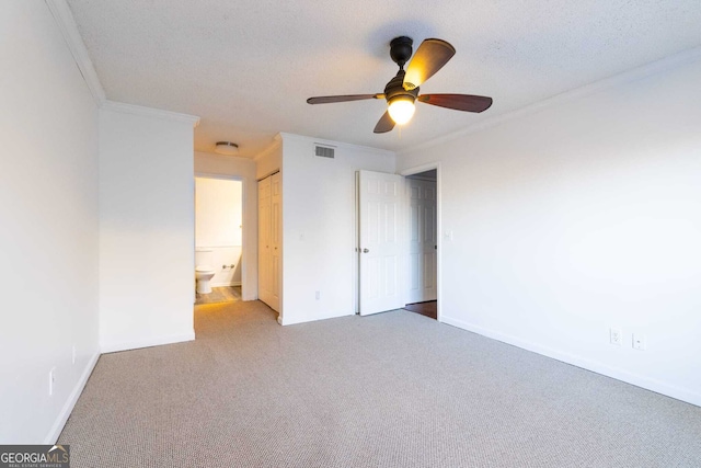 unfurnished bedroom featuring ensuite bath, carpet floors, ceiling fan, and crown molding