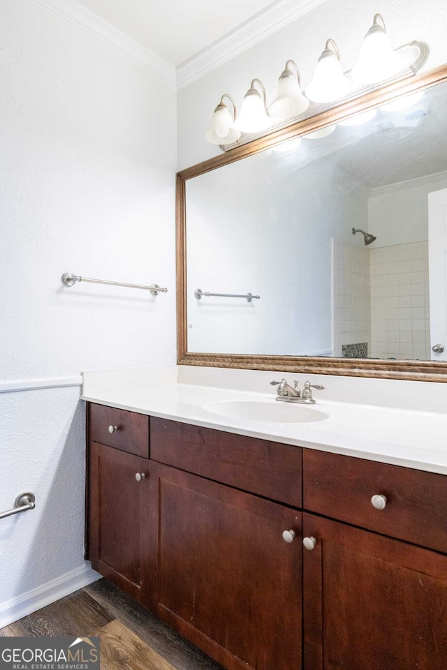 bathroom with hardwood / wood-style flooring, ornamental molding, walk in shower, and vanity