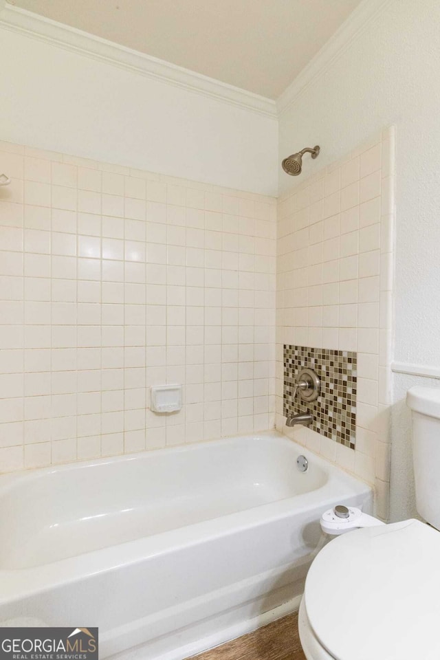 bathroom featuring toilet, wood-type flooring, ornamental molding, and tiled shower / bath