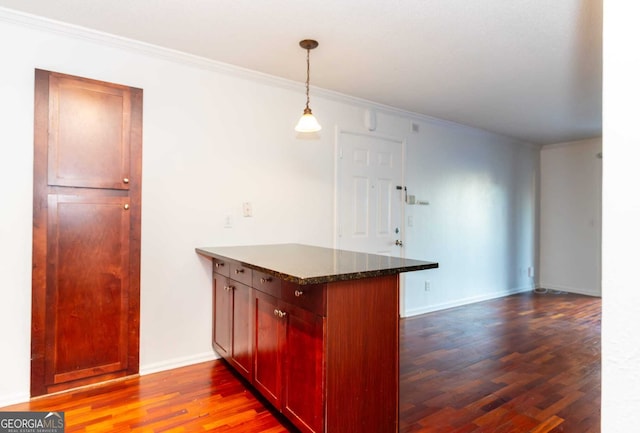 kitchen featuring kitchen peninsula, dark stone countertops, crown molding, and pendant lighting