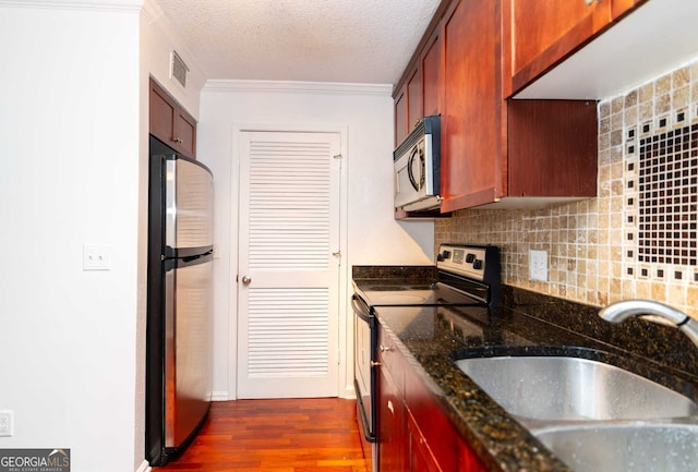 kitchen featuring a textured ceiling, tasteful backsplash, dark stone counters, appliances with stainless steel finishes, and sink