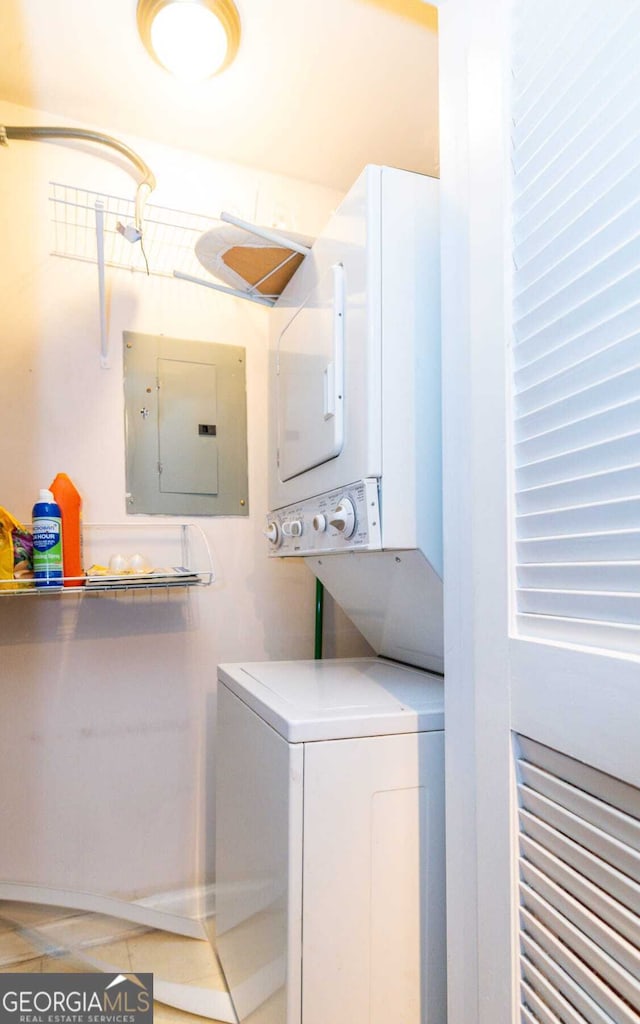 laundry area featuring electric panel, stacked washing maching and dryer, and tile patterned floors