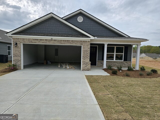 view of front of house featuring a porch, brick siding, driveway, and a garage