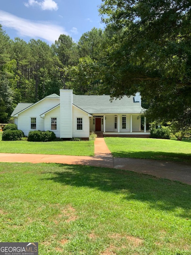 ranch-style home featuring covered porch and a front lawn