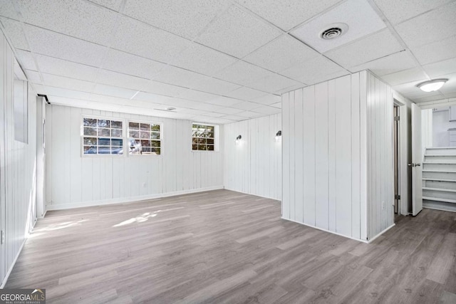 spare room featuring a paneled ceiling and light hardwood / wood-style floors