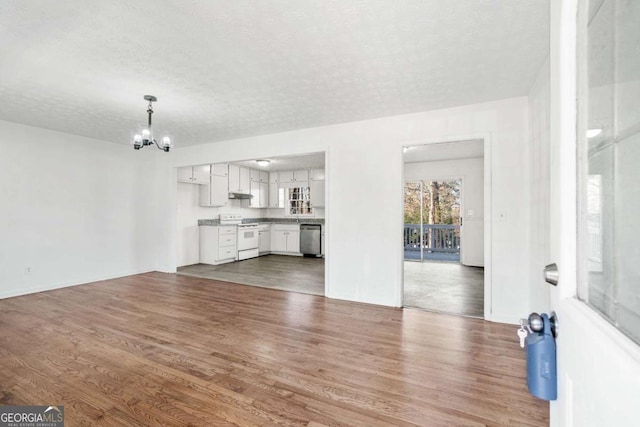 unfurnished living room with dark hardwood / wood-style flooring, a textured ceiling, and an inviting chandelier