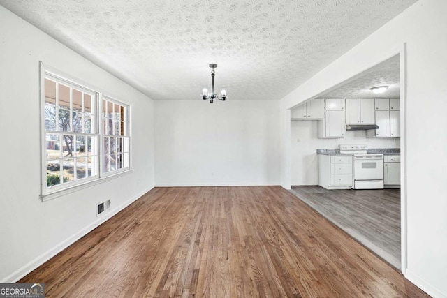 unfurnished dining area with dark hardwood / wood-style flooring, a textured ceiling, and a chandelier