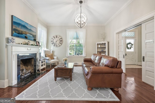 living room featuring dark hardwood / wood-style floors, crown molding, a high end fireplace, and an inviting chandelier