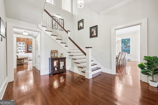 staircase featuring hardwood / wood-style floors, ornamental molding, a high ceiling, and a chandelier