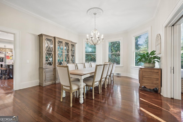 dining room featuring dark hardwood / wood-style flooring, ornamental molding, and a notable chandelier