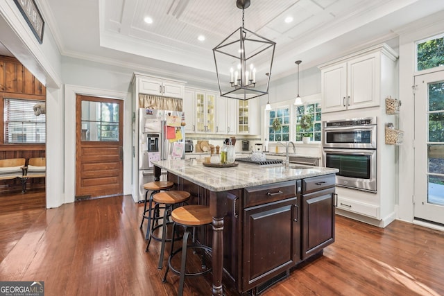 kitchen with appliances with stainless steel finishes, a breakfast bar, decorative light fixtures, white cabinets, and a center island