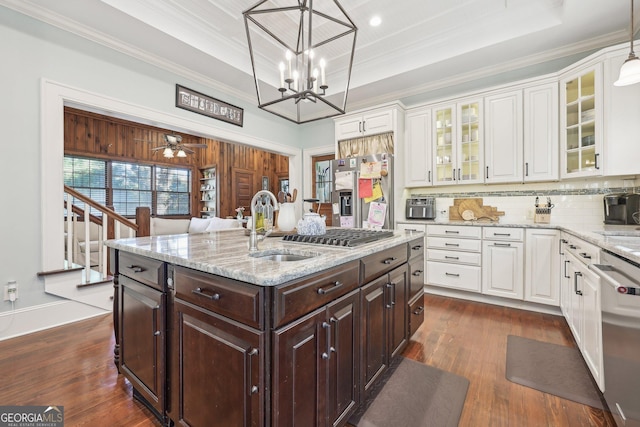 kitchen featuring dark brown cabinetry, ceiling fan with notable chandelier, stainless steel appliances, hanging light fixtures, and an island with sink