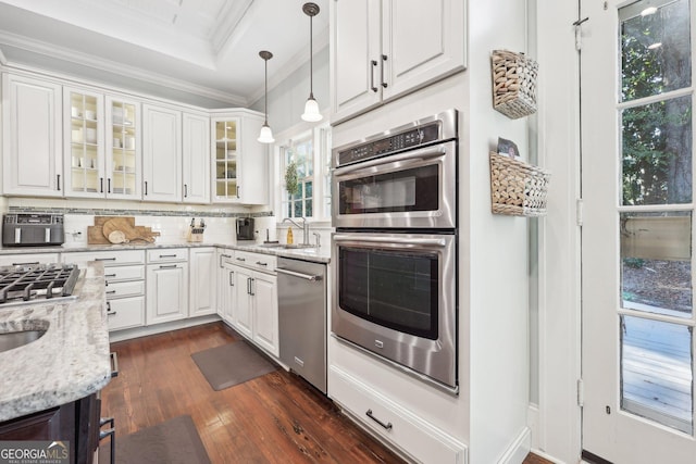 kitchen with light stone countertops, decorative backsplash, stainless steel appliances, white cabinetry, and hanging light fixtures