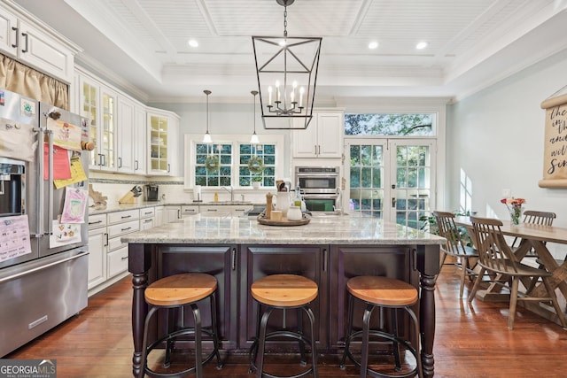 kitchen featuring white cabinets, a center island, hanging light fixtures, and appliances with stainless steel finishes