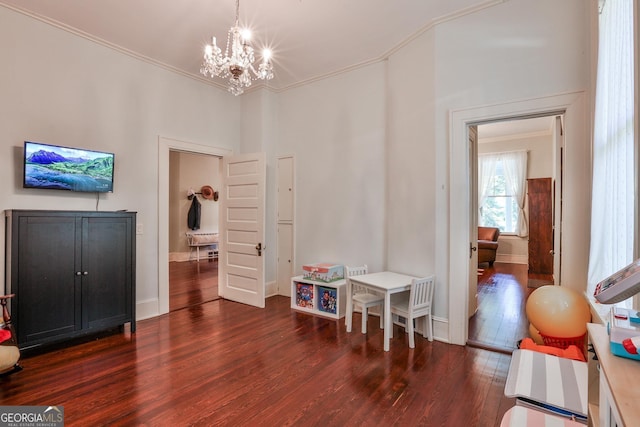 rec room with dark hardwood / wood-style flooring, crown molding, and a chandelier