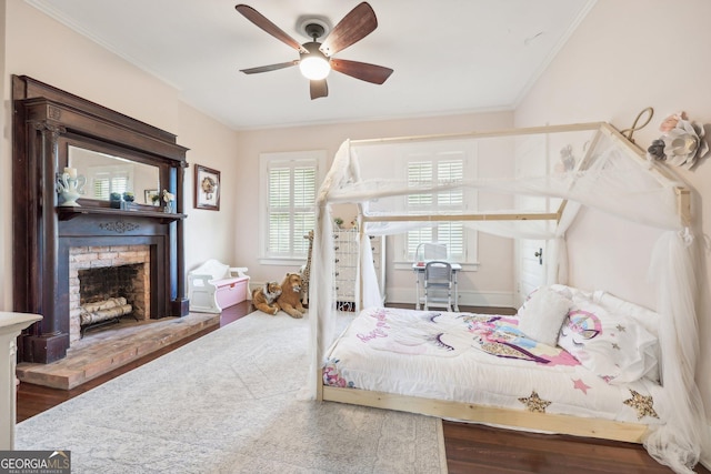 bedroom featuring a fireplace, wood-type flooring, ceiling fan, and ornamental molding