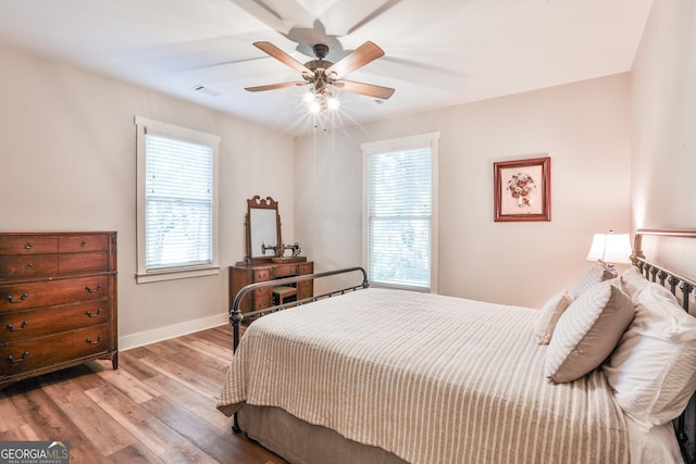 bedroom with multiple windows, ceiling fan, and light hardwood / wood-style floors