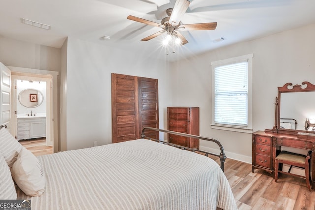 bedroom featuring ceiling fan, sink, ensuite bathroom, and light wood-type flooring