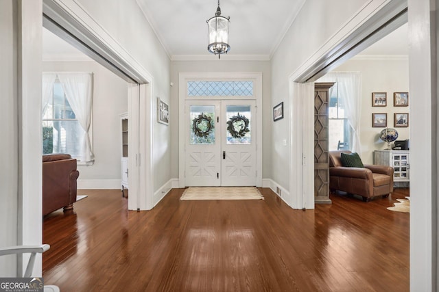 foyer featuring french doors, dark hardwood / wood-style floors, an inviting chandelier, and crown molding