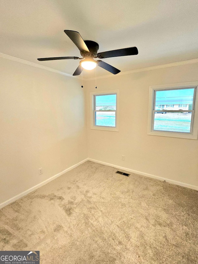 empty room with ornamental molding, ceiling fan, and carpet